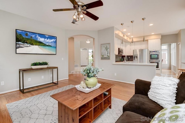 living room featuring ceiling fan, plenty of natural light, and light wood-type flooring