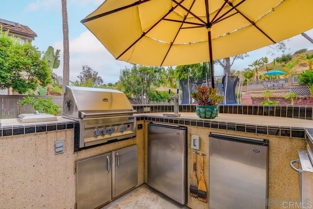 view of patio with an outdoor kitchen, grilling area, and a trampoline