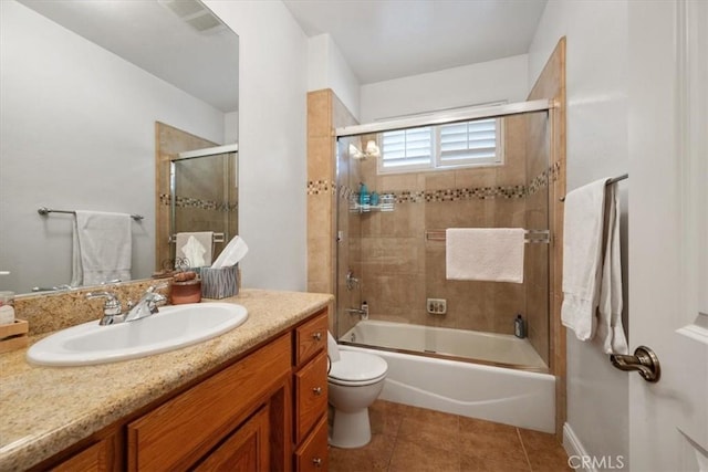 full bathroom with tile patterned flooring, vanity, combined bath / shower with glass door, and toilet