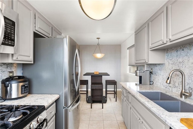 kitchen with gray cabinets, pendant lighting, tasteful backsplash, sink, and light tile patterned floors