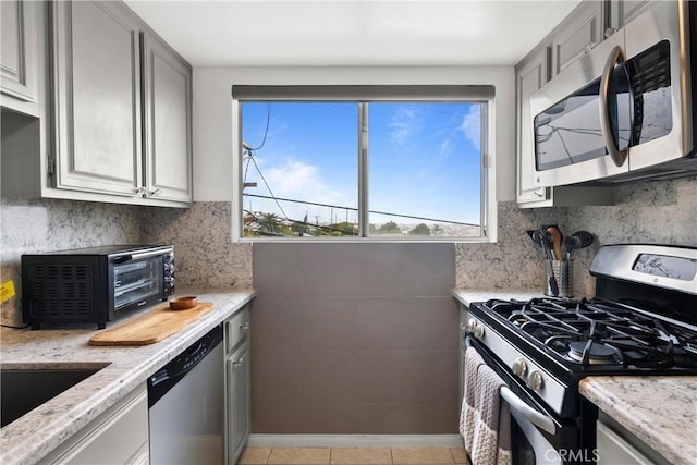 kitchen featuring gray cabinets, light stone countertops, and appliances with stainless steel finishes