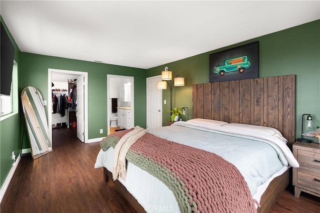 bedroom with ensuite bathroom, a spacious closet, dark hardwood / wood-style floors, and a closet