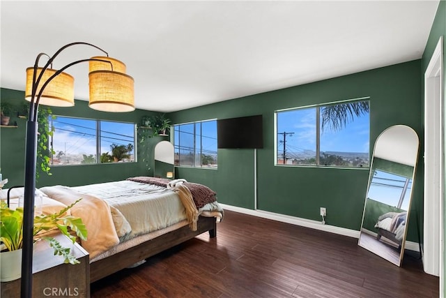 bedroom with dark hardwood / wood-style floors and multiple windows