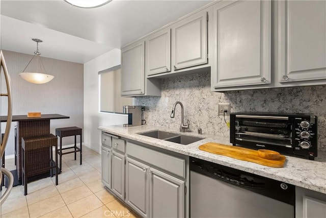 kitchen featuring gray cabinets, sink, stainless steel dishwasher, light tile patterned floors, and light stone counters