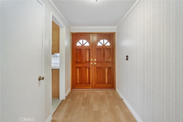 doorway featuring crown molding and light hardwood / wood-style floors