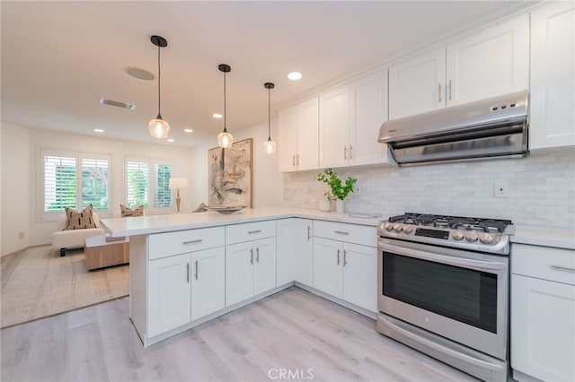 kitchen featuring light countertops, stainless steel gas range, a peninsula, and exhaust hood