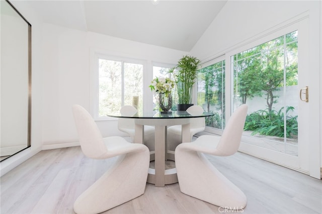 dining space with vaulted ceiling and light wood-type flooring