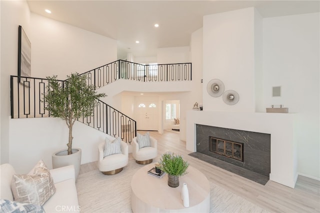 living room with a premium fireplace, a high ceiling, and light wood-type flooring