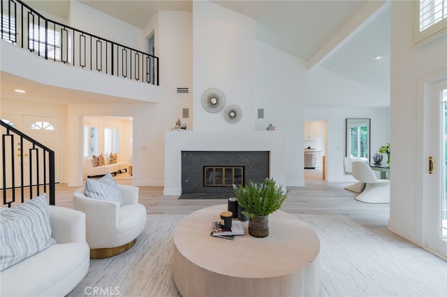 living room with stairs, wood finished floors, a towering ceiling, and a premium fireplace