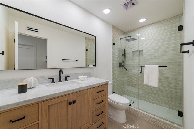 full bathroom with toilet, vanity, a shower stall, and visible vents