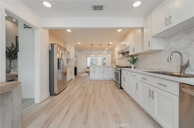 kitchen featuring stainless steel appliances, a peninsula, a sink, visible vents, and light wood-type flooring