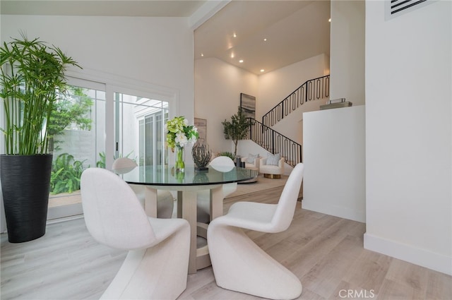 dining room featuring visible vents, stairway, wood finished floors, high vaulted ceiling, and baseboards