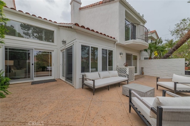 back of property featuring stucco siding, an outdoor hangout area, a patio area, a balcony, and a tiled roof