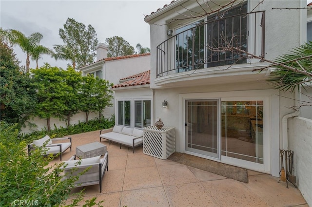 back of house with stucco siding, an outdoor hangout area, a patio area, a balcony, and a tiled roof