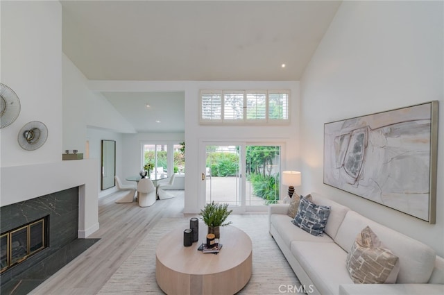 living area featuring a premium fireplace, high vaulted ceiling, wood finished floors, and recessed lighting