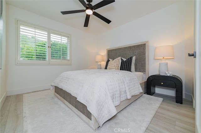 bedroom featuring a ceiling fan, baseboards, and wood finished floors