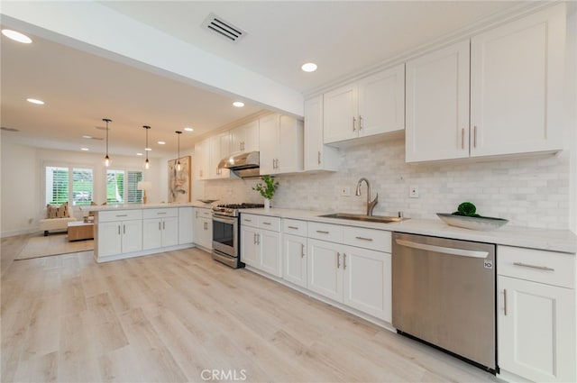 kitchen featuring stainless steel appliances, visible vents, a sink, a peninsula, and under cabinet range hood