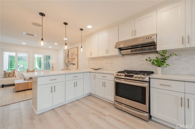 kitchen featuring light countertops, a peninsula, light wood-type flooring, stainless steel gas range oven, and extractor fan