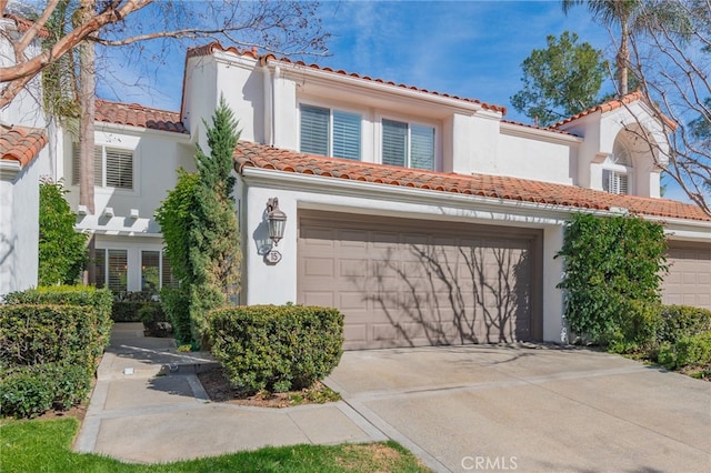 mediterranean / spanish house featuring a tile roof, concrete driveway, and stucco siding