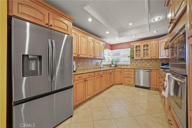 kitchen with light tile patterned flooring, appliances with stainless steel finishes, tasteful backsplash, ornamental molding, and a raised ceiling