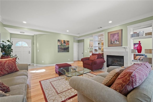 living room featuring built in features, ornamental molding, and light hardwood / wood-style flooring