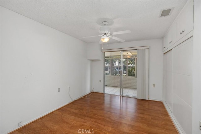 empty room featuring hardwood / wood-style flooring, ceiling fan, and a textured ceiling