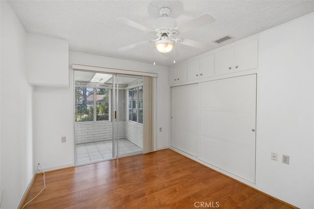 empty room featuring ceiling fan, hardwood / wood-style floors, and a textured ceiling