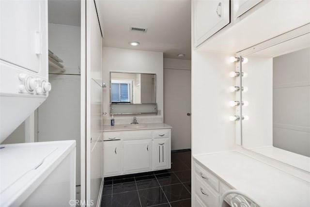 bathroom featuring stacked washer and dryer, vanity, and tile patterned floors