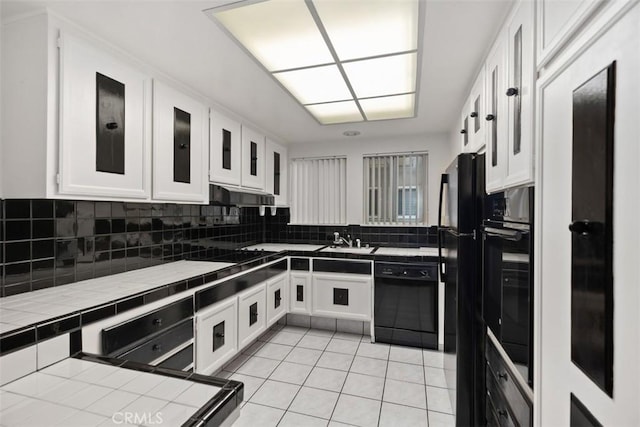 kitchen with white cabinetry, sink, tile countertops, and black appliances