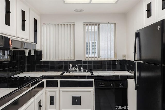 kitchen featuring sink, backsplash, tile counters, black appliances, and white cabinets