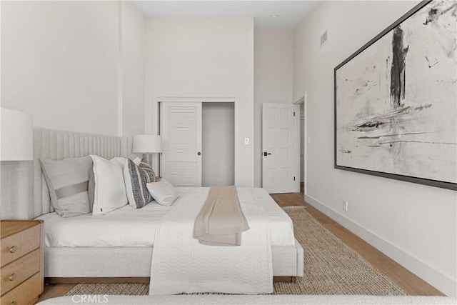 bedroom featuring a towering ceiling and light wood-type flooring