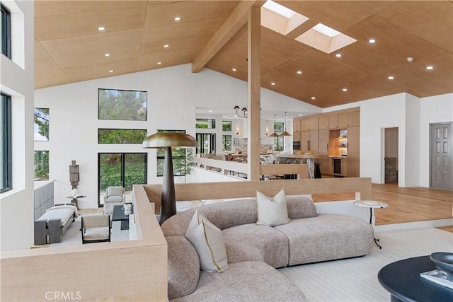 living room with beamed ceiling, wood ceiling, high vaulted ceiling, and a skylight