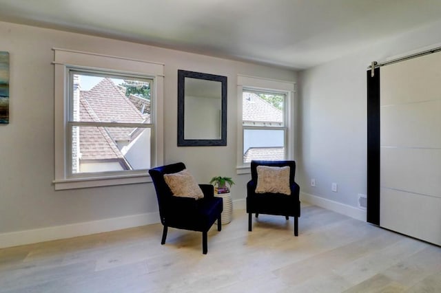 living area with a barn door and light wood-type flooring