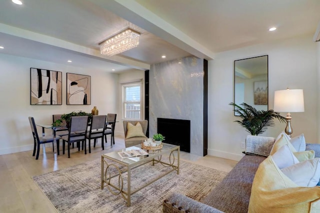 living room featuring an inviting chandelier, a fireplace, and light wood-type flooring