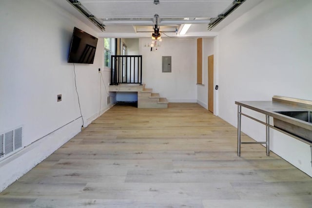 interior space featuring electric panel and light hardwood / wood-style flooring