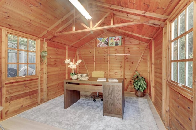 carpeted home office featuring a wealth of natural light, lofted ceiling with beams, and wood walls