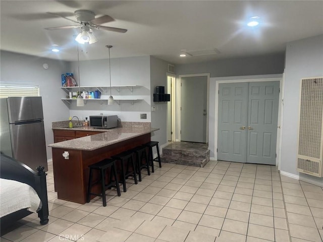 kitchen featuring a breakfast bar, sink, light tile patterned floors, appliances with stainless steel finishes, and ceiling fan