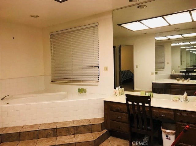 bathroom with a relaxing tiled tub, vanity, and tile patterned flooring