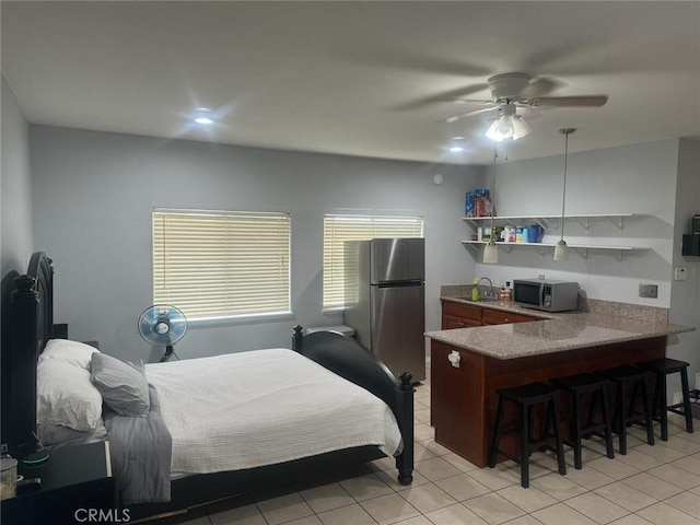 bedroom with light tile patterned floors, stainless steel fridge, and ceiling fan