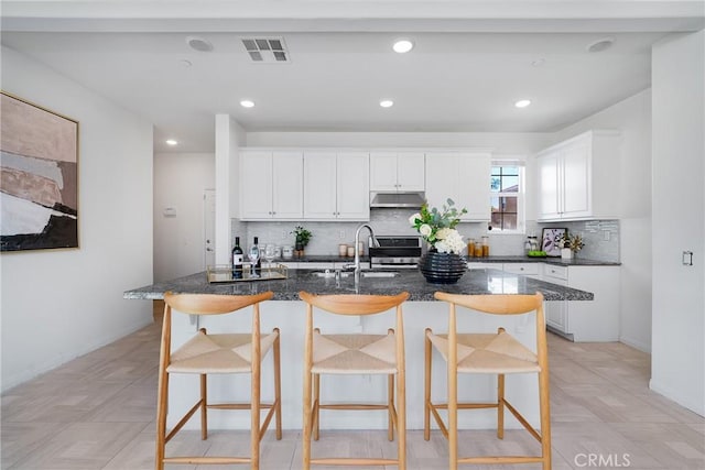 kitchen with white cabinetry, sink, a kitchen breakfast bar, and a center island with sink