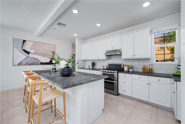 kitchen with backsplash, double oven range, a breakfast bar area, and white cabinets