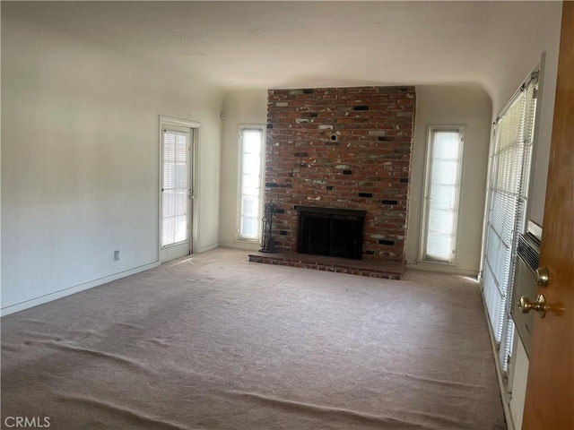 unfurnished living room with a brick fireplace and light colored carpet