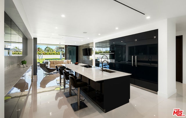 kitchen featuring sink, a breakfast bar area, light tile patterned floors, a wall of windows, and a large island