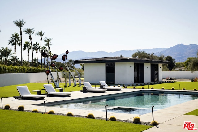 view of pool with a mountain view, an outbuilding, a patio area, and a lawn