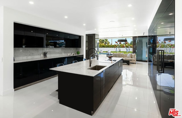 kitchen with tasteful backsplash, sink, a spacious island, and light tile patterned flooring