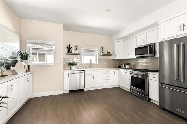 kitchen featuring dark hardwood / wood-style floors, white cabinetry, sink, decorative backsplash, and stainless steel appliances