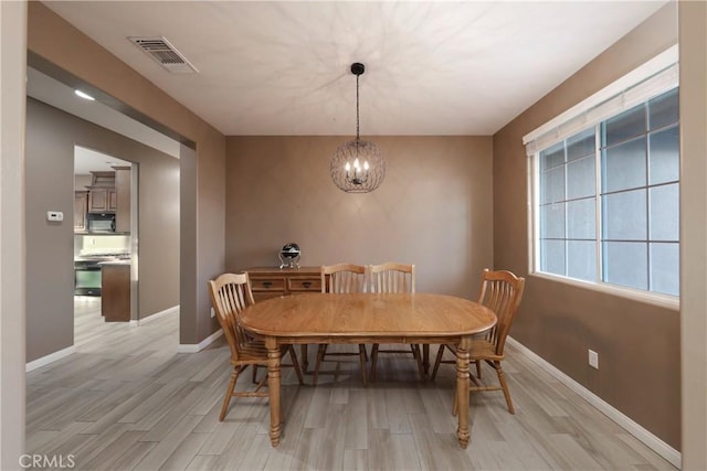 dining area with an inviting chandelier and light hardwood / wood-style flooring