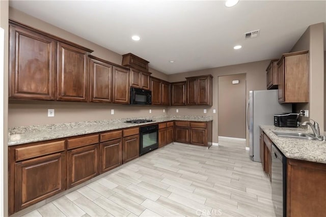 kitchen featuring stainless steel appliances, light stone countertops, sink, and light hardwood / wood-style flooring