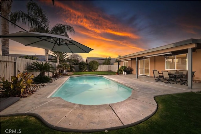 pool at dusk with a patio area