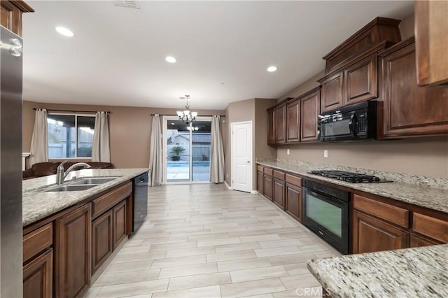 kitchen featuring pendant lighting, a healthy amount of sunlight, sink, and black appliances